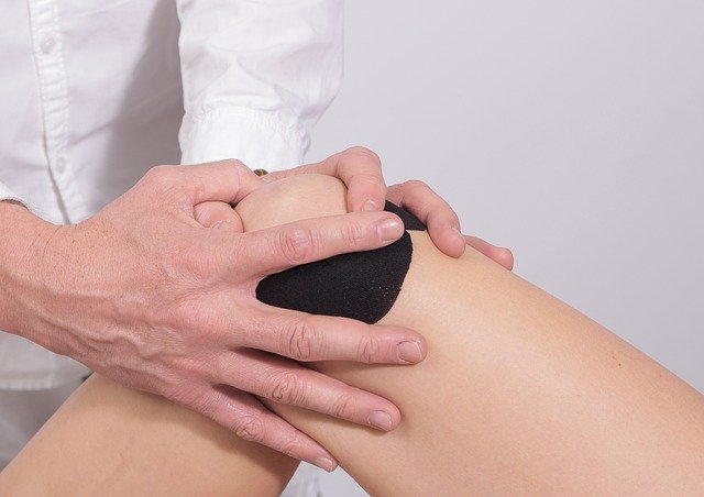 Zu sehen ist das getapte Knie einer Frau, um deutlich zu machen, dass auch Gelenkschmerz zu den Selen Mangel Symptomen gehört.